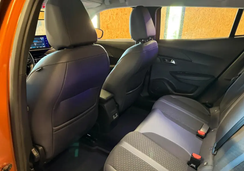 Vue intérieure arrière droite de la banquette noire et grise du Peugeot 2008 orange, avec dossiers des sièges avant visibles.