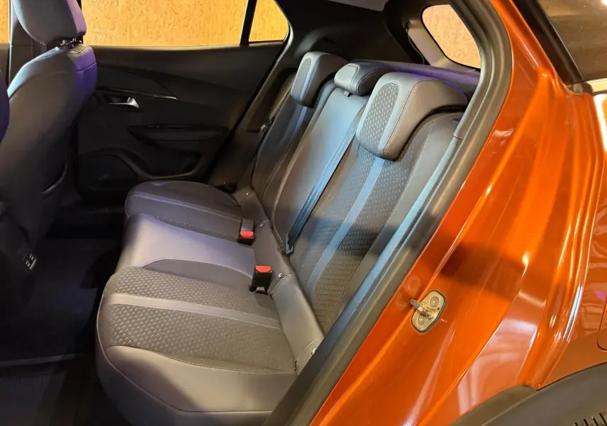 Vue intérieure côté droit sur la banquette arrière grise du Peugeot 2008 orange métallisé avec ceintures de sécurité visibles.