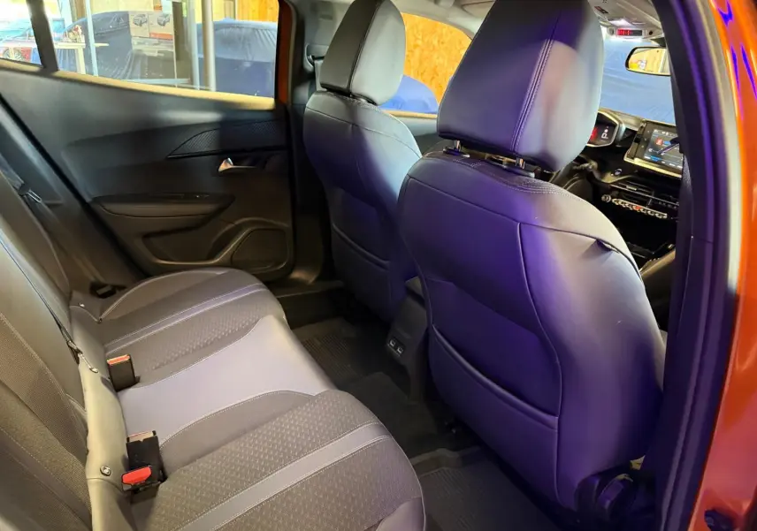 Vue intérieure arrière droite du Peugeot 2008 orange 2020, montrant la banquette 1/3-2/3 et les sièges avant en tissu gris.