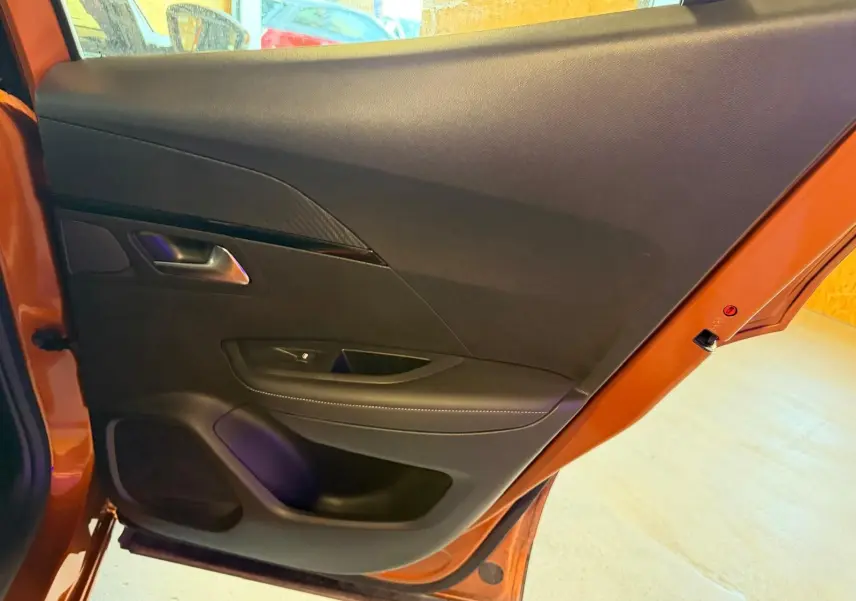 Vue intérieure de la porte arrière gauche orange du Peugeot 2008 2020 avec garniture noire et poignée métal.