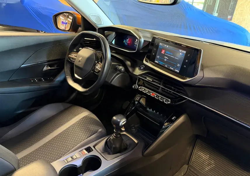 Intérieur avant droit du Peugeot 2008 orange 2020, volant compact, écran tactile et levier de vitesse manuel visibles.