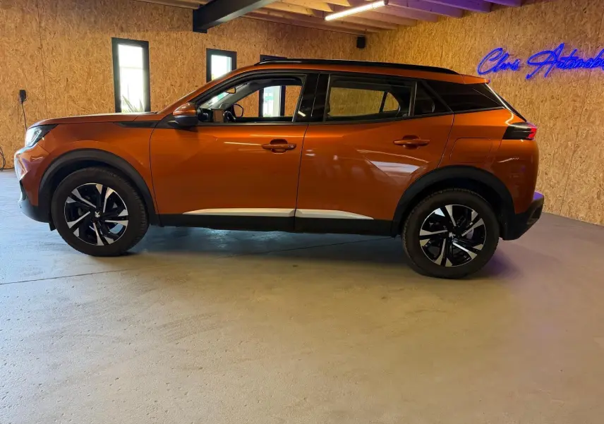 Peugeot 2008 orange vue de profil côté gauche, avec jantes alliage bi-ton et toit noir contrasté.
