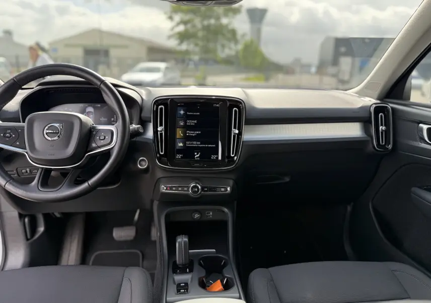 Vue intérieure avant du Volvo XC40 T5 hybride rechargeable, tableau de bord noir avec écran central tactile et volant multifonction.