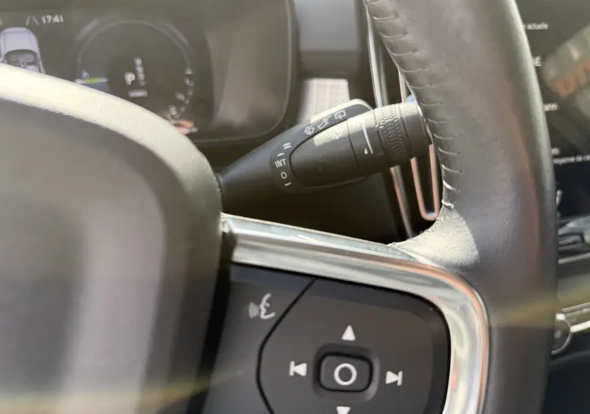 Gros plan sur le volant noir et la commande des essuie-glaces du Volvo XC40 blanc Crystal Metal, version hybride rechargeable.