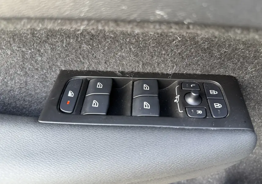 Gros plan sur les commandes de lève-vitres et rétroviseurs sur la porte intérieure d’un Volvo XC40 blanc.