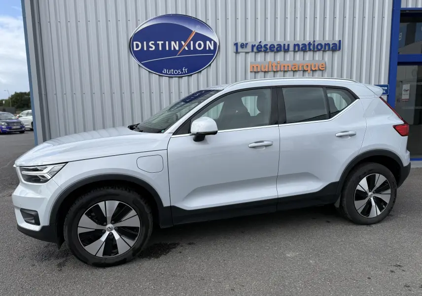 Vue de profil côté gauche d'un Volvo XC40 blanc Crystal Metal hybride rechargeable, avec jantes spécifiques et prise de recharge visible.