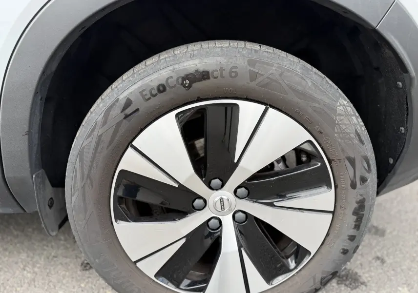 Gros plan sur la roue avant droite du Volvo XC40 blanc Crystal Metal, mettant en valeur la jante bicolore moderne.