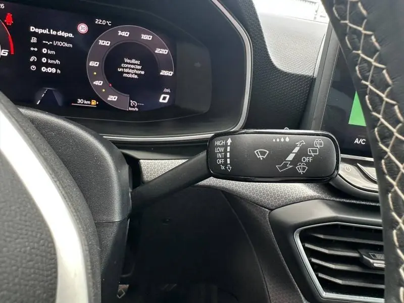 Vue rapprochée du commodo d'essuie-glace à droite du volant cuir d'une SEAT Leon 2025, tableau de bord numérique visible.