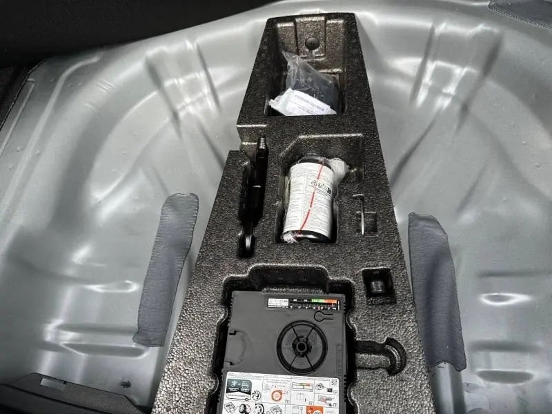Détail du coffre de la SEAT LEON 2025 avec kit de réparation pneu et compartiments de rangement intégrés.