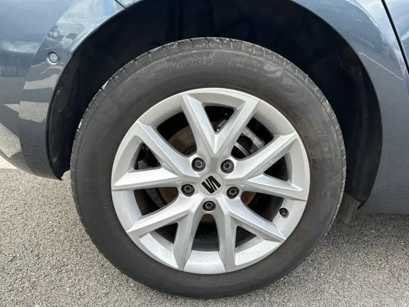 Gros plan sur la jante alu argentée et le pneu du côté avant droit d'une SEAT LEON noir minuit métallisée.