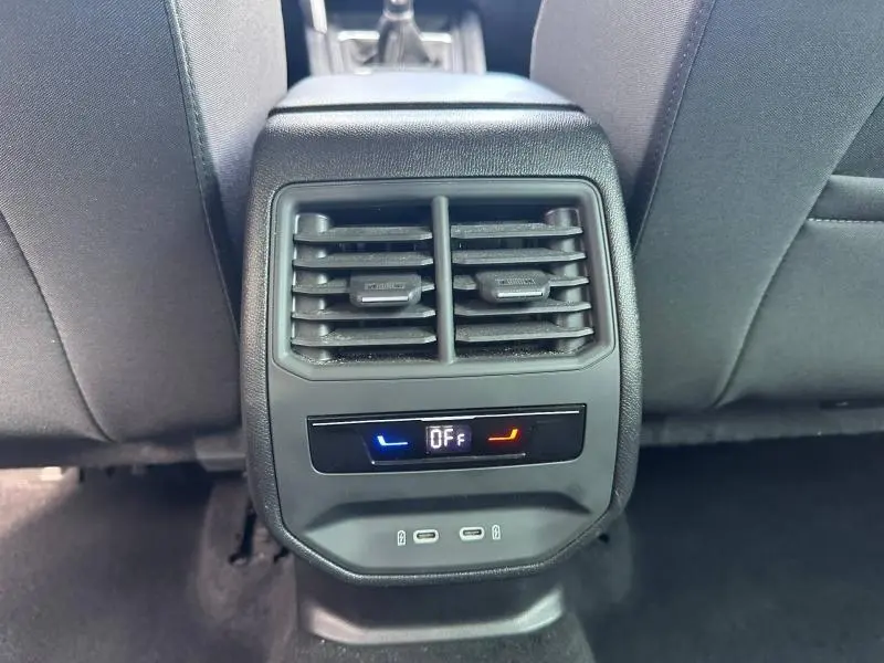 Vue rapprochée de la console arrière noire avec bouches d’aération et commandes climatisation éteintes sur la SEAT Leon 2025.