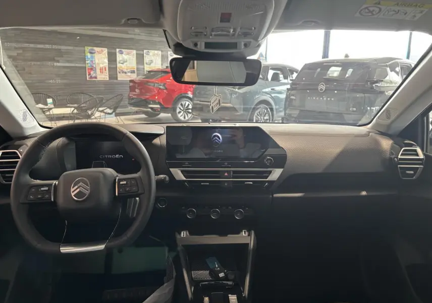 Vue intérieure avant du tableau de bord noir du Citroën C4 1.2i Hybride avec écran tactile central et volant multifonctions.