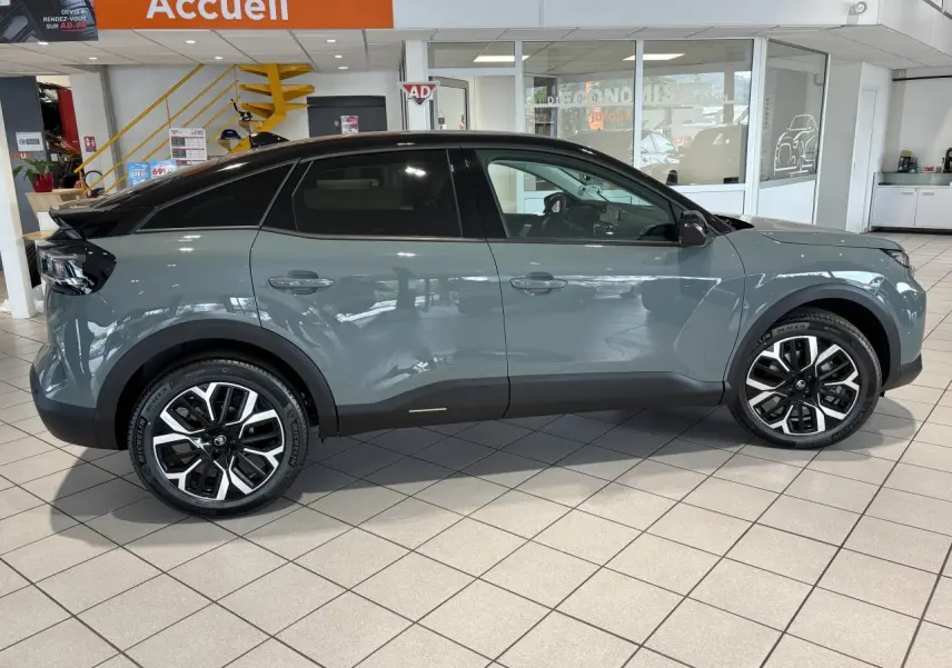 Profil côté gauche d'une Citroën C4 2026 vert Manhattan avec toit noir Perla Nera en showroom.