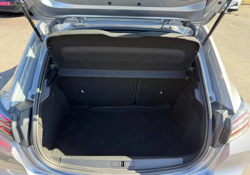 Coffre ouvert vu de dessus d'une Peugeot 208 gris Artense, montrant un espace de chargement propre et vide.