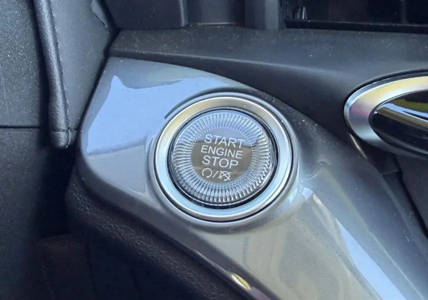 Gros plan sur le bouton Start Engine Stop dans l'habitacle de la Fiat 500 e Ocean Green métal 2024.