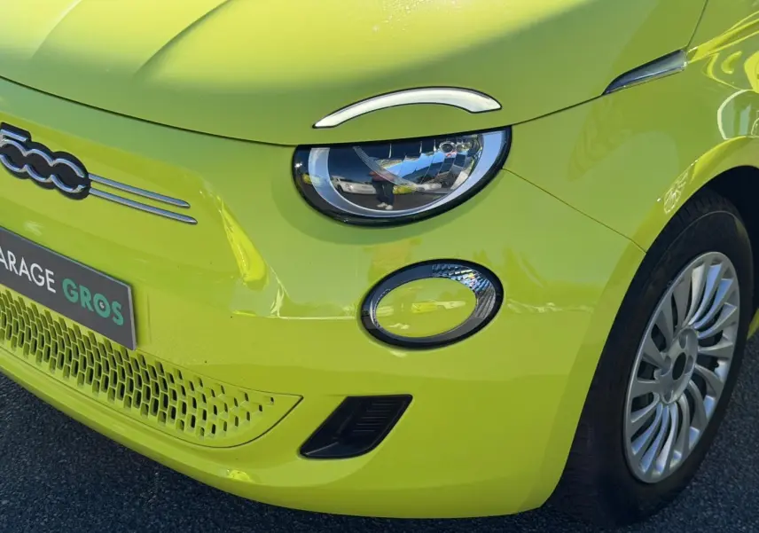 Gros plan sur l'avant droit de la Fiat 500 électrique Ocean Green métal avec phares ronds et jante argentée.