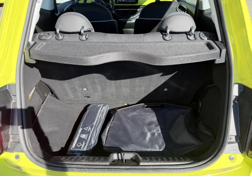 Coffre ouvert vu de l'arrière d'une FIAT 500 électrique Ocean Green métal avec accessoires de rangement noirs.