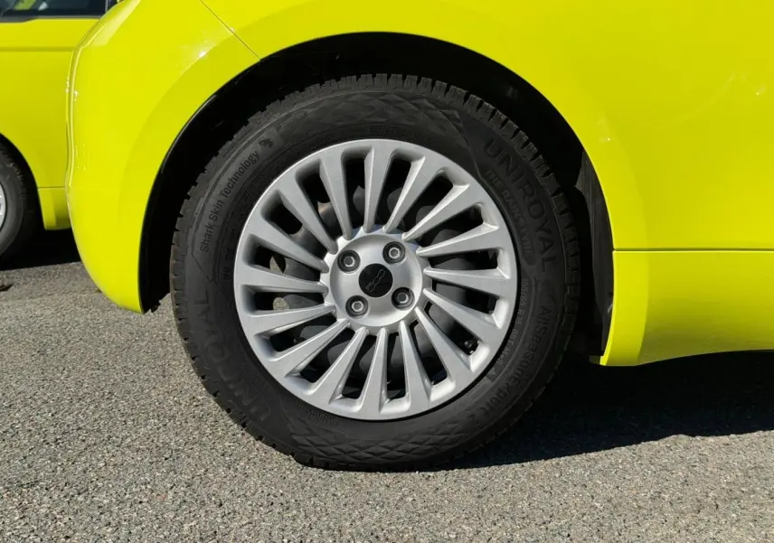 Gros plan sur la roue arrière droite d'une FIAT 500 électrique 2024 en jaune vif avec jante argentée à rayons fins.