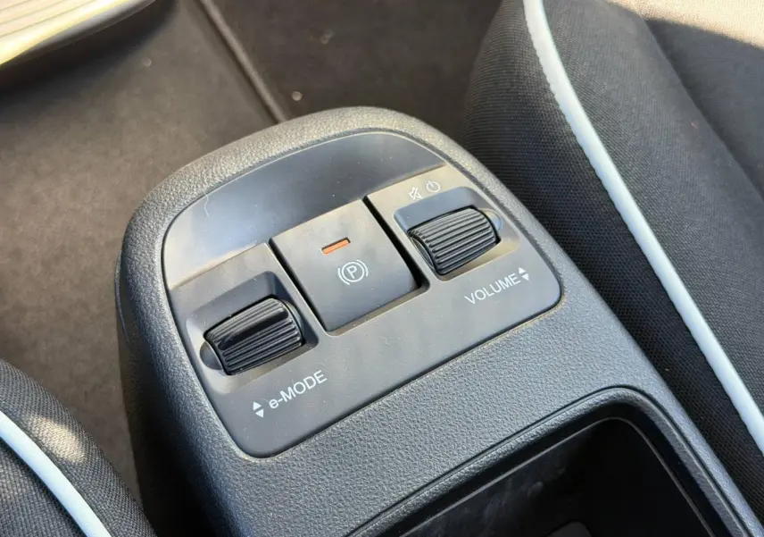 Gros plan sur la console centrale de la Fiat 500 e 95ch Pack Confort MY23 avec commandes e-Mode, frein à main électrique et réglage volume.
