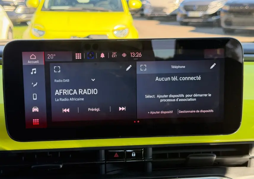 Vue intérieure du tableau de bord de la Fiat 500 e Ocean Green, avec écran tactile multimédia allumé.