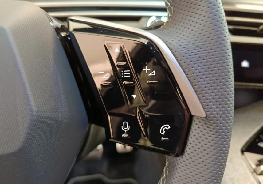 Gros plan sur les commandes tactiles noires du volant cuir perforé côté gauche du Peugeot 3008 HYBRID 145 GT 2025.