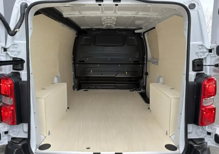 Vue arrière ouverte du Peugeot Expert Fourgon blanc Icy 2025 montrant l'espace de chargement avec plancher et parois boisées.