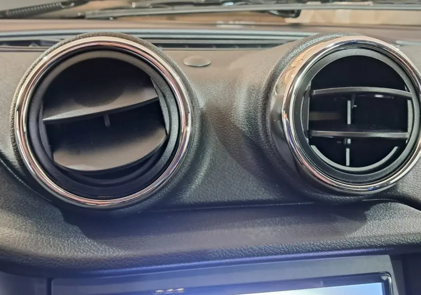 Détail intérieur montrant les deux aérateurs ronds chromés du tableau de bord de l'AIXAM AMBITION bleu 2025.