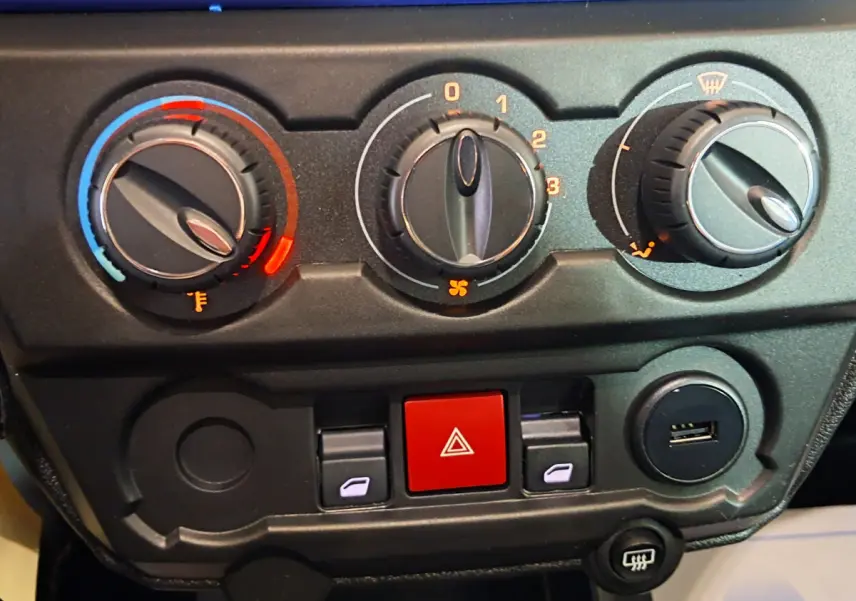 Gros plan sur la console centrale de l'AIXAM AMBITION 2025 bleu, montrant les commandes de climatisation et boutons de sécurité.