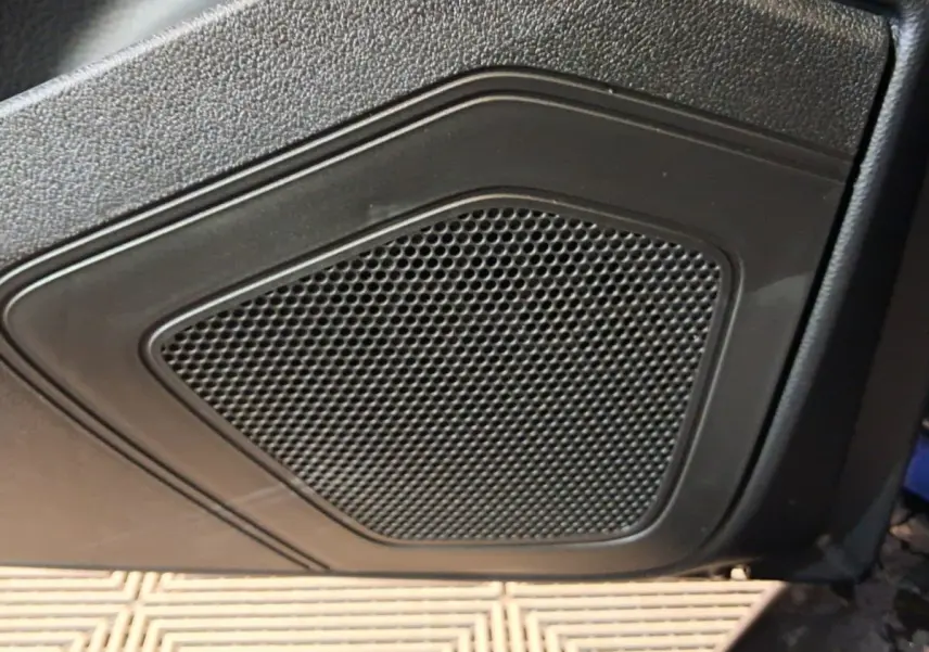 Gros plan sur le haut-parleur intégré à la porte intérieure noire de l'AIXAM AMBITION 2025.