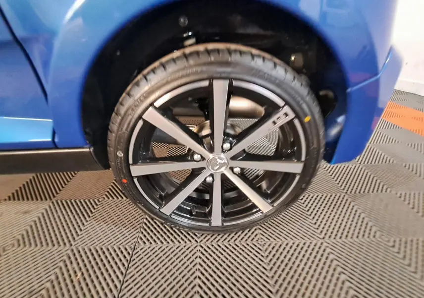 Gros plan sur la roue avant gauche d'une Aixam Ambition bleu 2025 avec jante noire à rayons argentés.