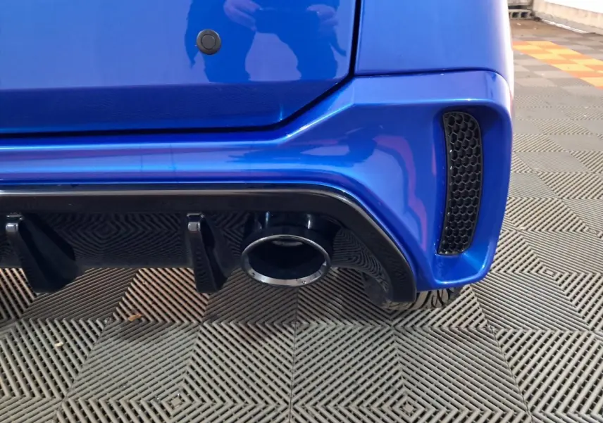 Gros plan sur l'arrière droit bleu de l'AIXAM AMBITION 2025, mettant en valeur la sortie d'échappement et le diffuseur noir.