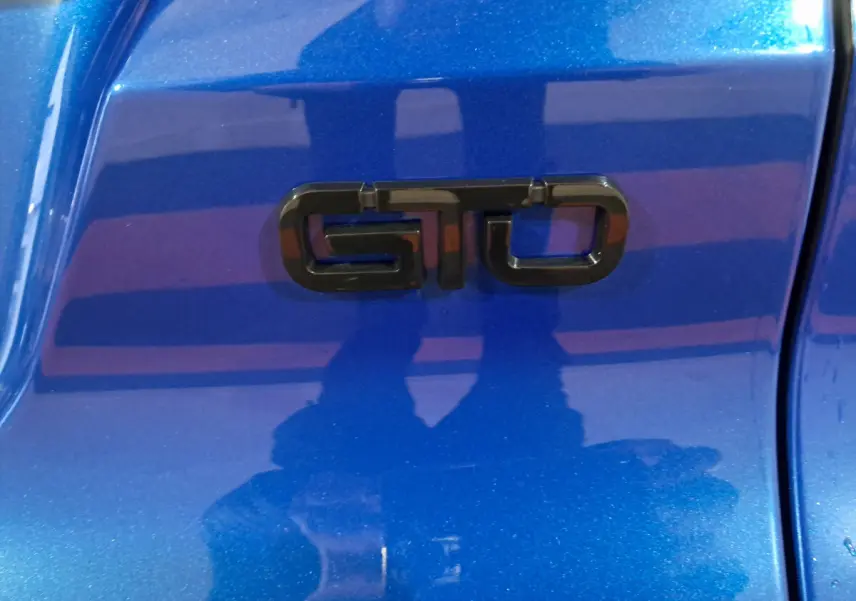 Gros plan sur l’inscription GTO noire sur la carrosserie bleue métallisée de l’AIXAM AMBITION 2025.