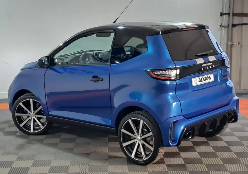 Vue 3/4 arrière droite d'une AIXAM AMBITION 0.5 CITY GTO bleu métallisé avec jantes noires et toit noir.