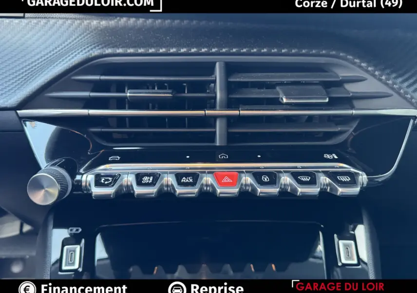 Gros plan sur la console centrale noire brillante de la Peugeot 208 Hybrid 110, avec boutons chromés et aérateurs horizontaux.