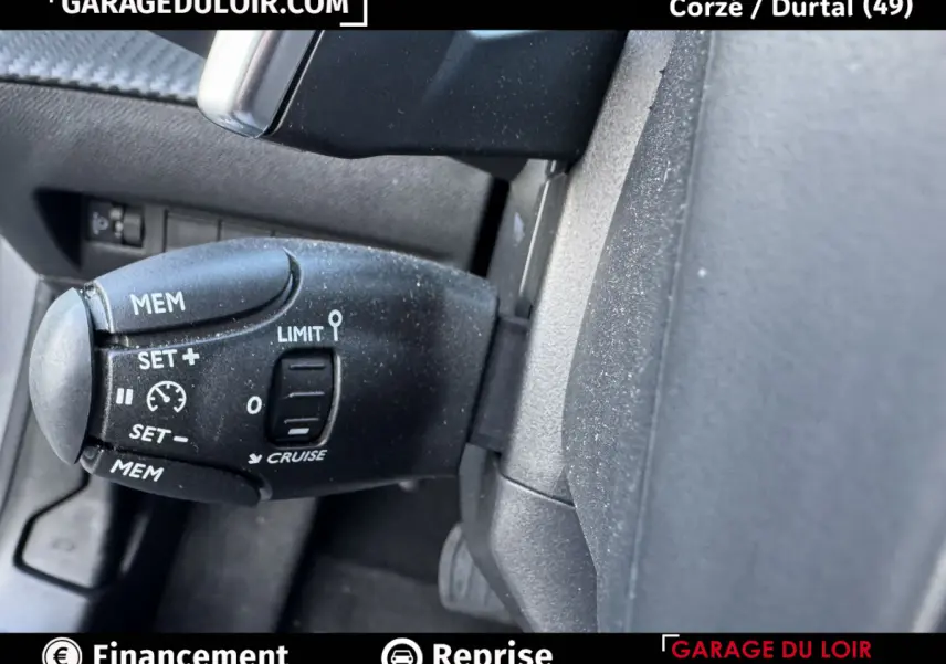 Gros plan sur la commande de régulateur de vitesse noire dans l’habitacle d’une Peugeot 208 gris clair.