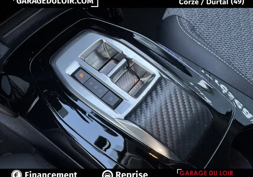 Gros plan sur la console centrale noire brillante de la Peugeot 208 Hybrid 110, avec levier de vitesses automatique et finition carbone.