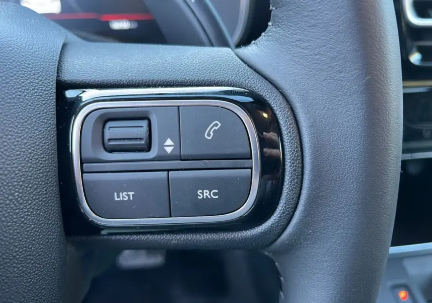 Gros plan sur les commandes gauche du volant cuir noir du Citroën C5 Aircross Hybrid 2025.