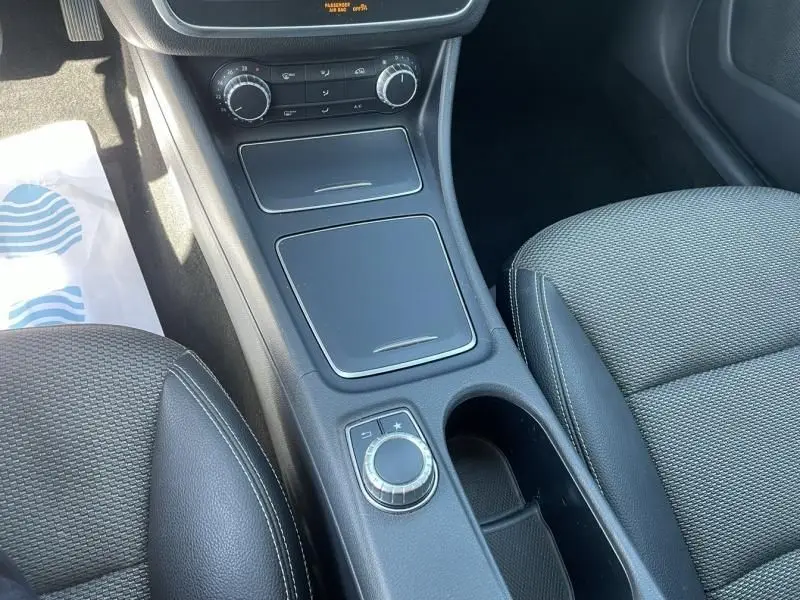 Vue rapprochée de la console centrale noire du Mercedes Classe CLA Shooting Brake 200 d avec commandes et sièges en tissu gris.