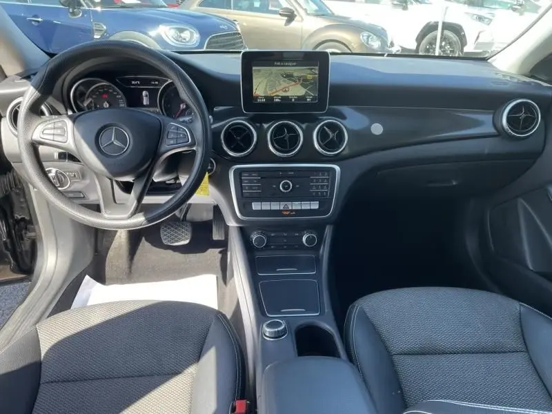 Vue intérieure avant de la Mercedes Classe CLA Shooting Brake noire de 2017, avec tableau de bord et écran central visible.