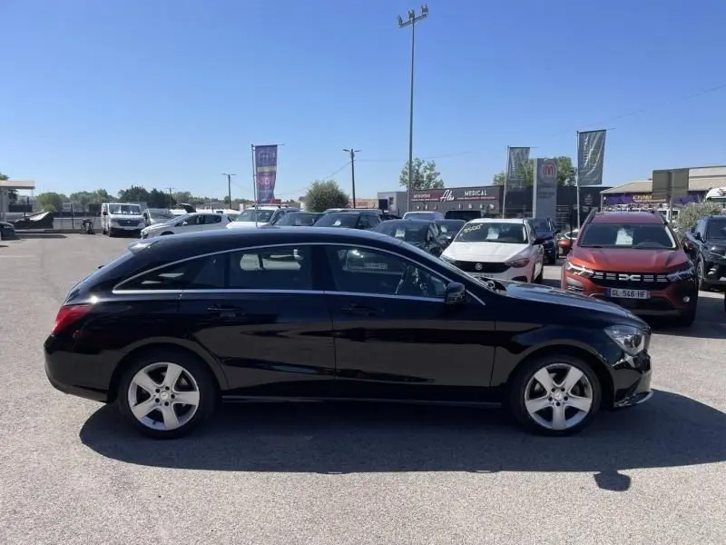 Vue de profil côté gauche d'une Mercedes Classe CLA Shooting Brake noire garée en extérieur, avec jantes argentées visibles.