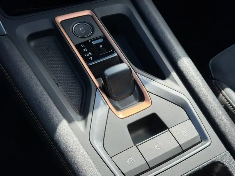 Gros plan sur la console centrale noire avec levier de vitesse automatique et contour cuivré du CUPRA Formentor blanc Nevada 2025.