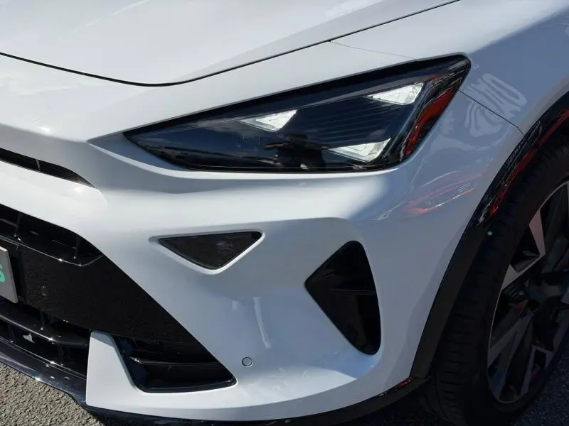 Gros plan sur l'avant droit blanc métallisé du CUPRA Formentor 1.5 eTSI Hybrid avec phare LED et jante noire.