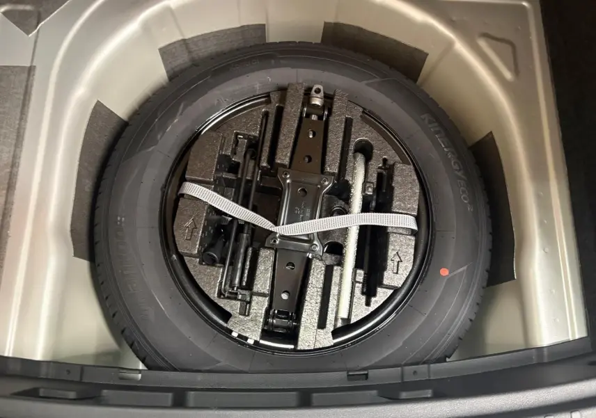 Vue plongeante sur la roue de secours et ses outils dans le coffre du Skoda Scala gris argent 2024.