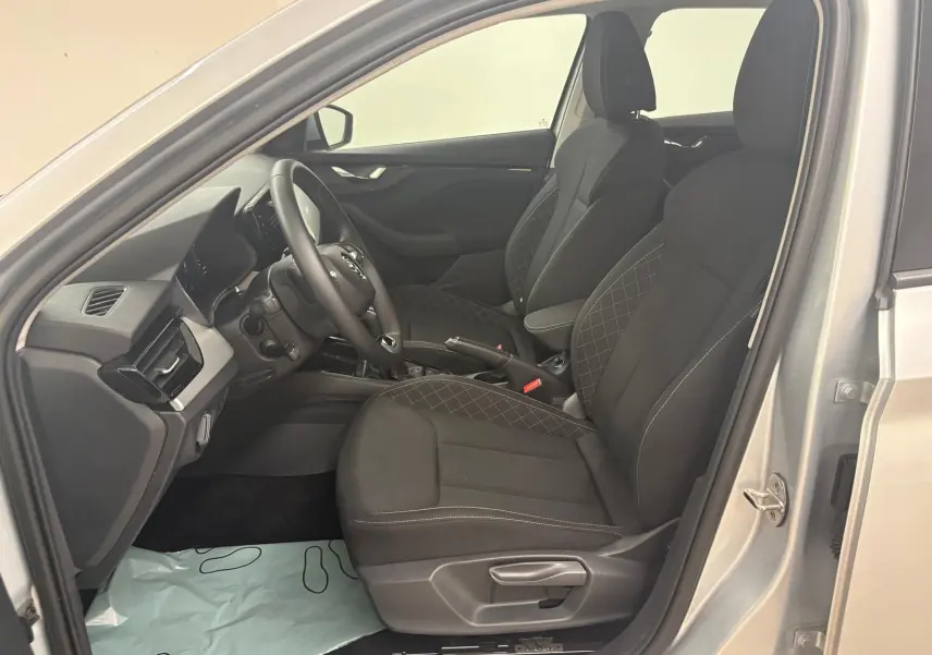 Vue intérieure côté conducteur de la Skoda Scala gris argent 2024, sièges tissu noir avec surpiqûres contrastées.