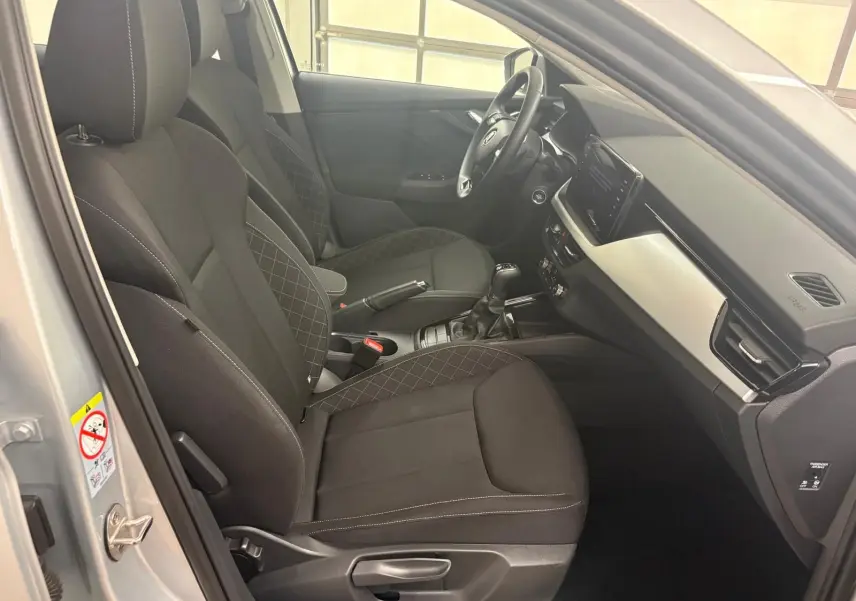 Intérieur côté conducteur de la Skoda Scala 2024 gris argent, sièges noirs avec surpiqûres et tableau de bord moderne.
