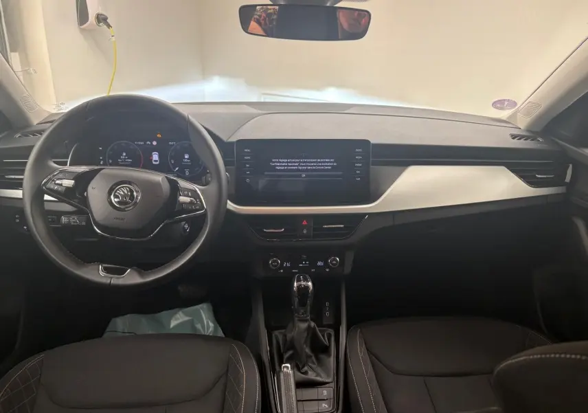 Vue intérieure frontale du tableau de bord de la Skoda Scala 2024 gris argent avec écran tactile et volant multifonction.