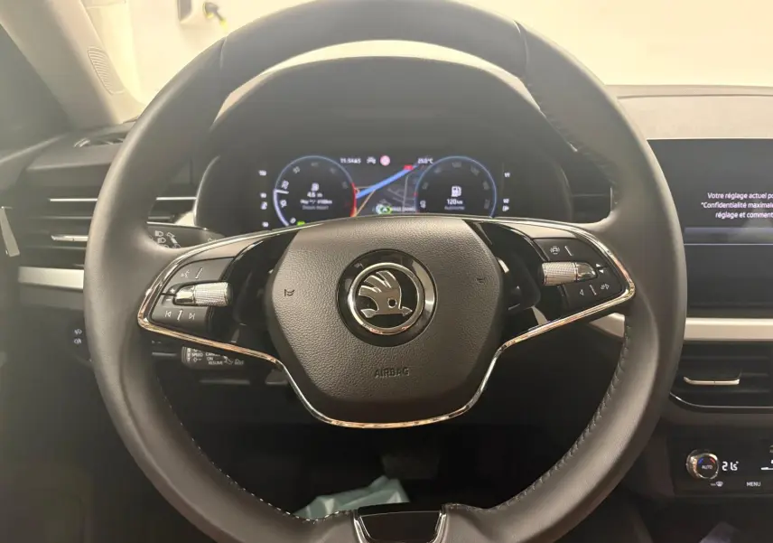 Vue intérieure centrée sur le volant noir du Skoda Scala 2024 avec tableau de bord numérique et commandes intégrées.