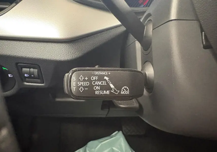 Gros plan sur la commande de régulateur de vitesse à gauche du volant dans l’habitacle gris du Skoda Scala 2024.