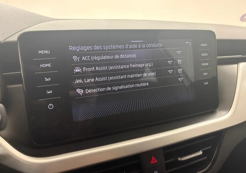 Écran tactile central du Skoda Scala 2024 gris argent affichant les réglages des aides à la conduite.