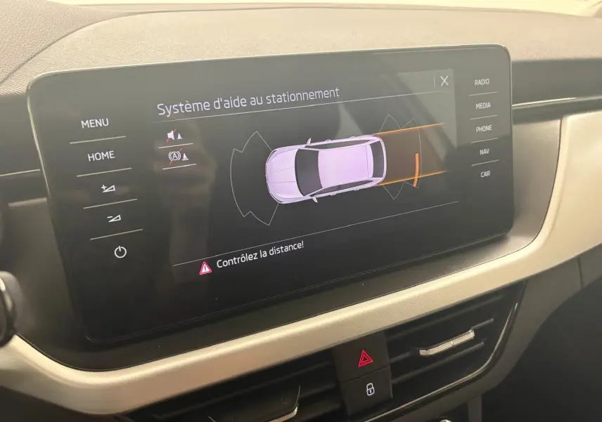 Écran central du Skoda Scala 2024 affichant le système d'aide au stationnement avec vue schématique du véhicule gris argent.